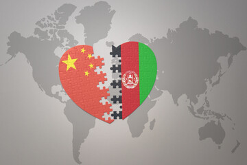puzzle heart with the national flag of china and afghanistan on a world map background. Concept.