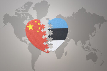 puzzle heart with the national flag of china and estonia on a world map background. Concept.