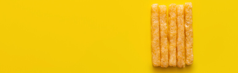 flat lay of delicious and crispy french fries on yellow, banner