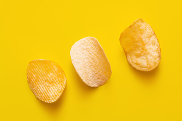 top view of different salty potato chips on yellow