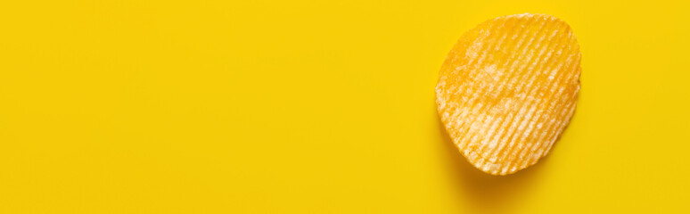 top view of single wavy and salty potato chip on yellow, banner