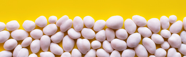 flay lay with row of tasty pine nuts on yellow background, banner