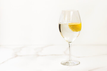 A glass of water with lemon on a light table for healthy life, energy, thermoregulation and normalization of digestion