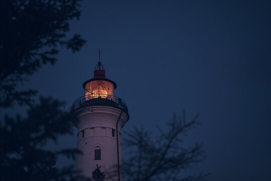 Lighthouse in the early morning hours through some branches. High quality photo