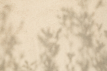 Blooming tree shadows on beige concrete rough textured background. Dark silhouette of leaves in...