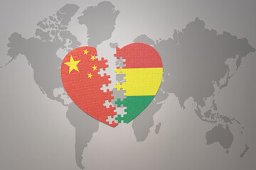 puzzle heart with the national flag of china and bolivia on a world map background. Concept.