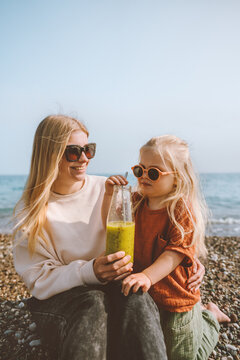 Mother And Child Drinking Smoothie  Outdoor Summer Vacations Family On Beach Travel Healthy Lifestyle Vegan Organic Beverage Fresh Fruit Juice