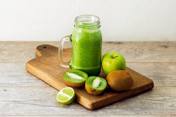 Healthy green smoothie from apple and kiwi on a wooden board. Front view.