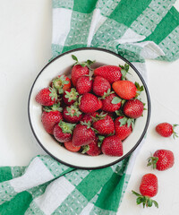 Red strawberries in a a round plate on a linen napkin. Healthy eating concept. Top view.