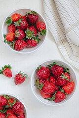 Ceramic white bowls with sweet juicy red strawberris on a white background. Top view.