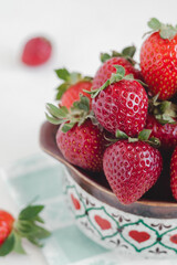 Fresh red strawberries close up in a ceramic bowl on a white background. Healthy eating concept.