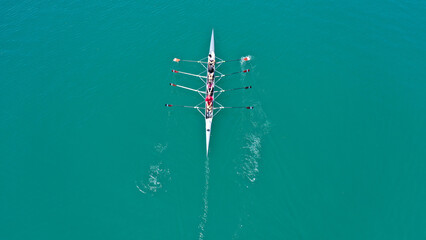 Aerial drone top down photo of sport canoe operated by team of young women in emerald sea waters