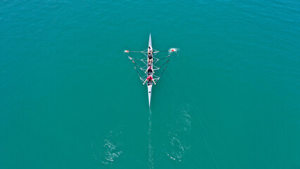 Aerial drone top down photo of sport canoe operated by team of young women in emerald sea waters