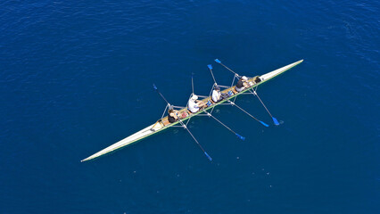 Aerial drone photo of sport canoe operated by team of young trained athletes in deep blue Aegean sea