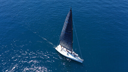 Aerial drone birds eye view photo of beautiful sailboat with blue sails cruising in the deep blue...