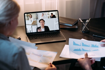 Web meeting. International video chat. Corporate telework. Diverse business team using laptop working from home with colleagues on screen in virtual office.