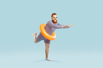 Funny crazy man with inflatable circle pretends to float on light azure background. Cheerful...