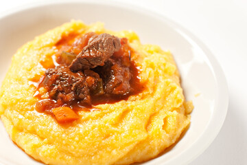 Polenta and beef stew on a plate. High quality photo.