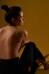 Back view of seductive woman with bare back sitting backwards on floor, with closed eyes. Brunette...