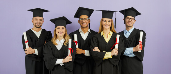 Diverse group of happy proud mixed race university students in graduate mortarboard hats and robes,...