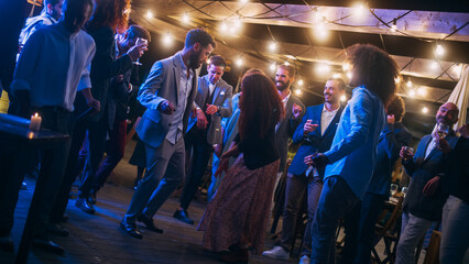 Beautiful Carefree Friends are Dancing Together and Celebrating an Evening Event at a Party . Diverse Multiethnic Young Adult People Have Fun at a Corporate Party in a Restaurant.