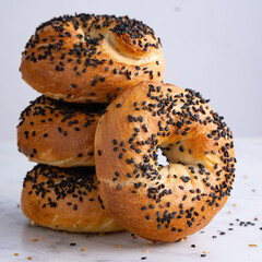 Stack of soft bagels topped with black sesame seeds on white background