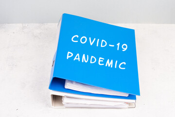 The words  Covid-19 pandemic are standing on a folder, outbreak of virus infectious disease, processing of the regualtions, documents for evidence