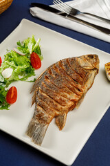 Overhead view of carp fish on white plate in restaurant