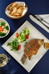 Overhead view of carp fish on white plate in restaurant