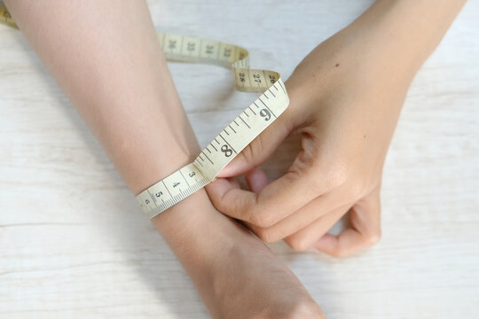 Female hand measuring wrist with a tape measure