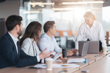 group of colleagues in formal clothing discussing business ideas at table and working together.