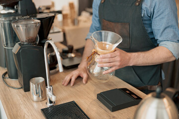 Close up of barista hands holds in his hands a glass vessel for making filter coffee. 