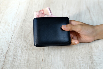 Closeup of a woman's hand holding a wallet with rupiah banknotes