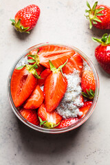 Homemade chia pudding with strawberry in jar, gray background.