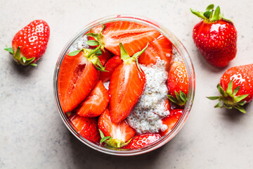 Homemade chia pudding with strawberry in jar, gray background.