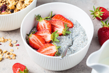 Homemade chia pudding with strawberry in white bowl, gray background.