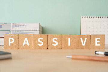 消極的・受動的のイメージ｜「PASSIVE」と書かれた積み木が置かれたデスク
