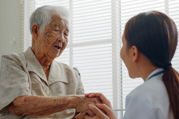 Fototapeta premium Asian doctor holding senior patient hand for encouragement and empathy, medical trust and support concept
