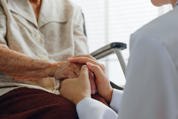 Closeup doctor holding senior patient hand for encouragement and empathy, medical trust and support concept