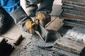 Worker in heavy industry or metallurgy beats scale off iron plates with hammer. Work with metal....