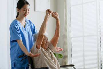 Young Asian woman nurse, caregiver assist a senior Asian woman to do physical therapy and exercise...