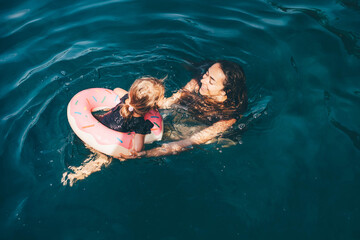 Baby girl swimming with Inflatable ring in the sea. Mother and daughter swimming in the sea.