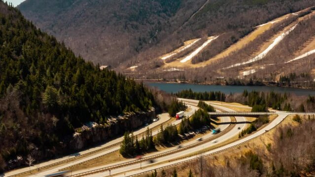 Drone Aerial hyper lapse time lapse of traffic on interstate with ski mountain and alpine lake in the spring HD 30p