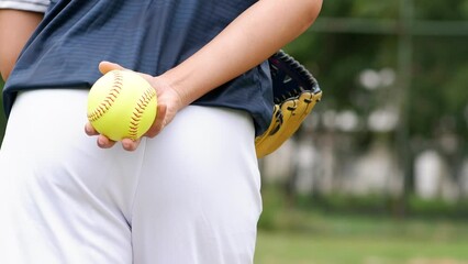 A young Softball player ready to peatch from his position in the outfield.holding a Softball ball in his hands while playing catch in the outfield - Powered by Adobe