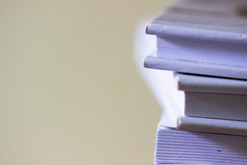 Stack of white books on light background. Close up of books. Free copy space.