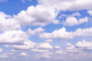 Blue cloudy sky with many beautiful white fluffy cumulus clouds in sunlight background texture