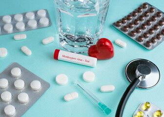 Blood sample tube for Monkeypox virus test. Blue background, thermometer, pill. Moneypox, is a...