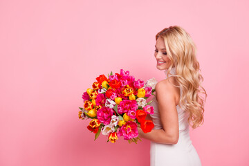 Photo of cheerful sweet woman wear white dress holding flowers bunch empty space isolated pink color background