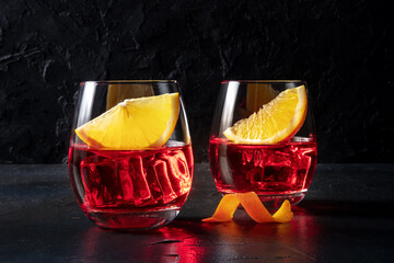 Campari aperitif with fresh orange slices, on a black background. An alcoholic drink, summer...