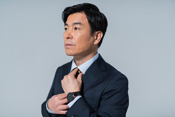 ネクタイを締める60代ビジネスマン